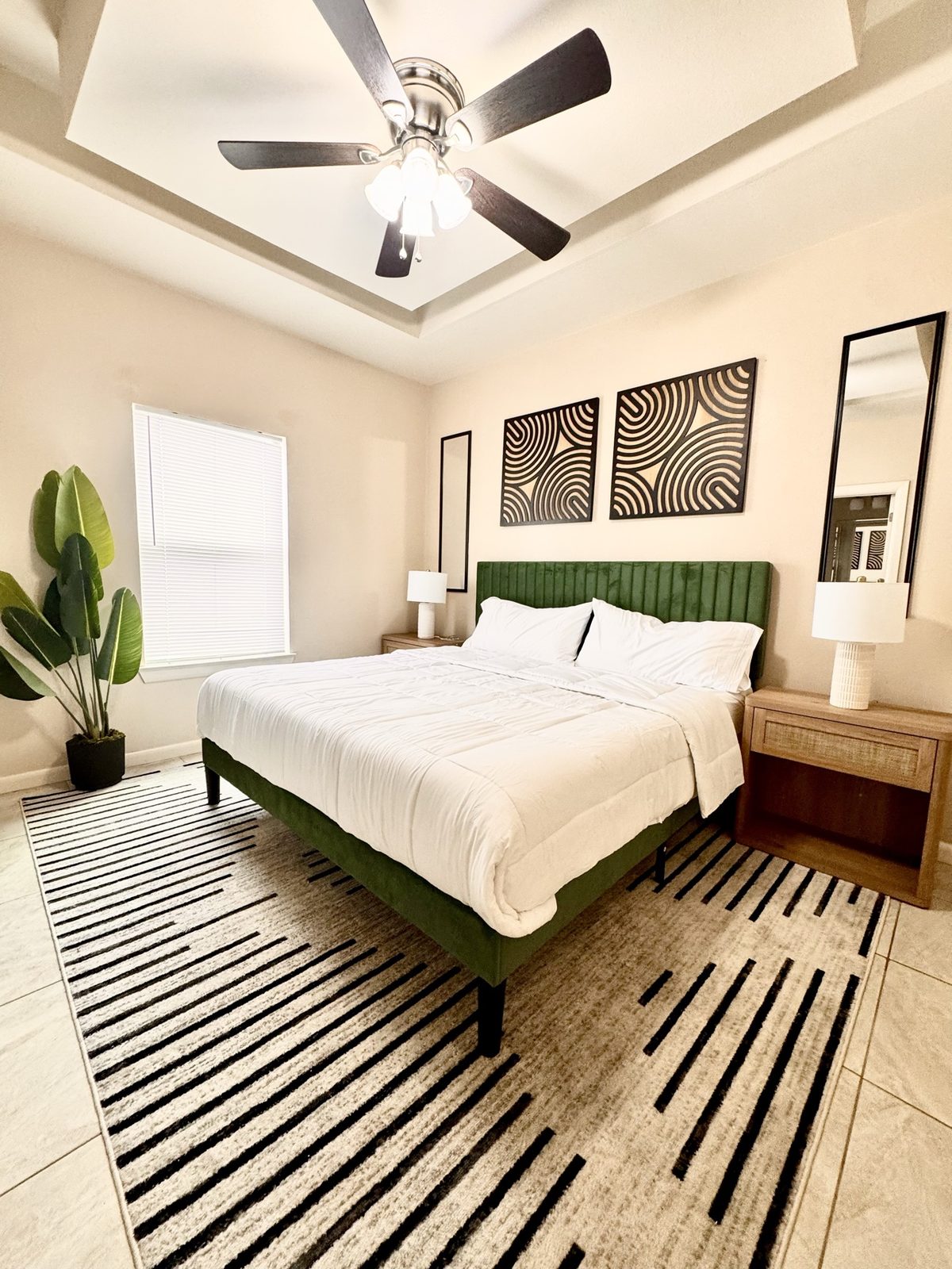 Airbnb bedroom with green velvet bed, graphic art and striped rug