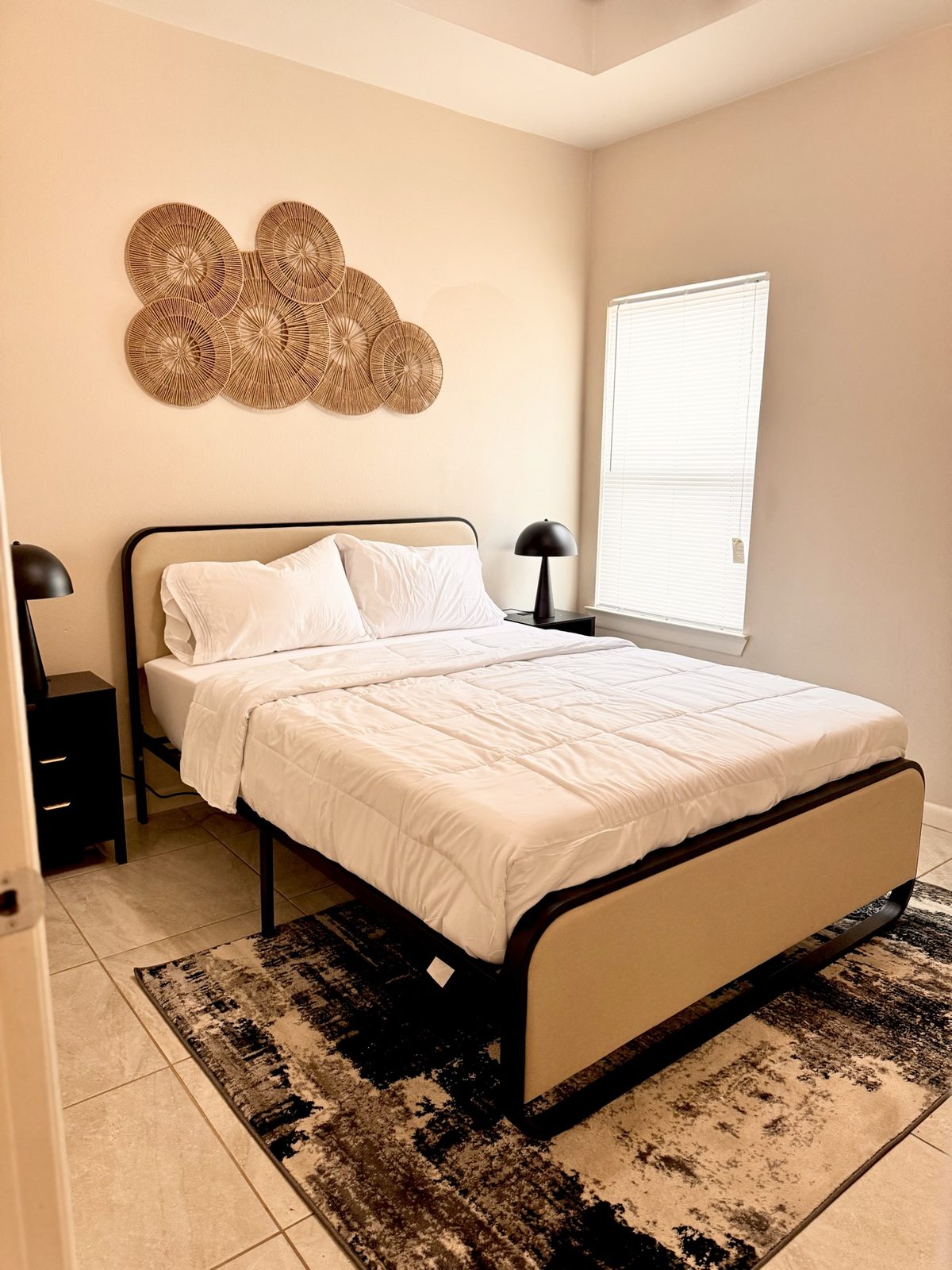 Airbnb neutral bedroom with rattan wall art and black accents