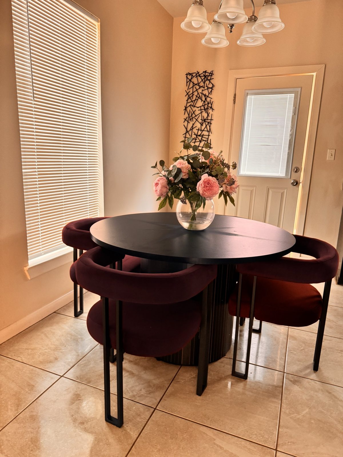 Airbnb dining nook with black table, burgundy velvet chairs and pink florals