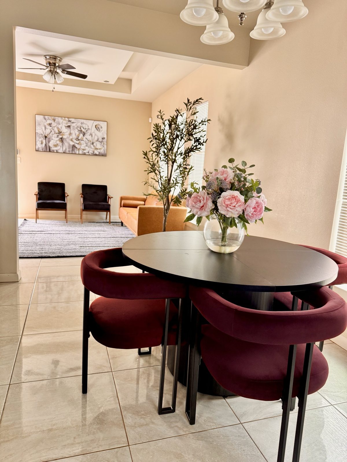 Airbnb open dining and living space with burgundy chairs and caramel sofa