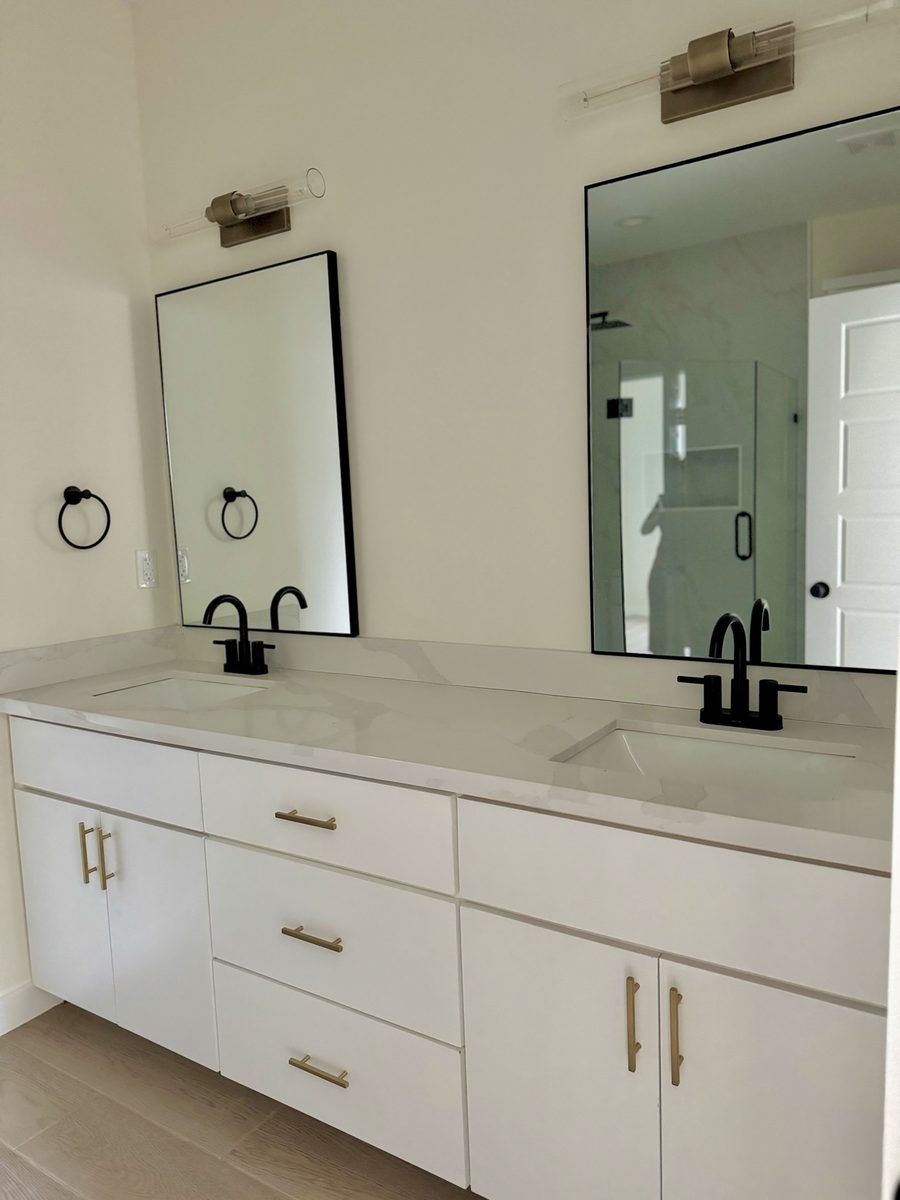 Primary bathroom with double vanity, black faucets and gold hardware